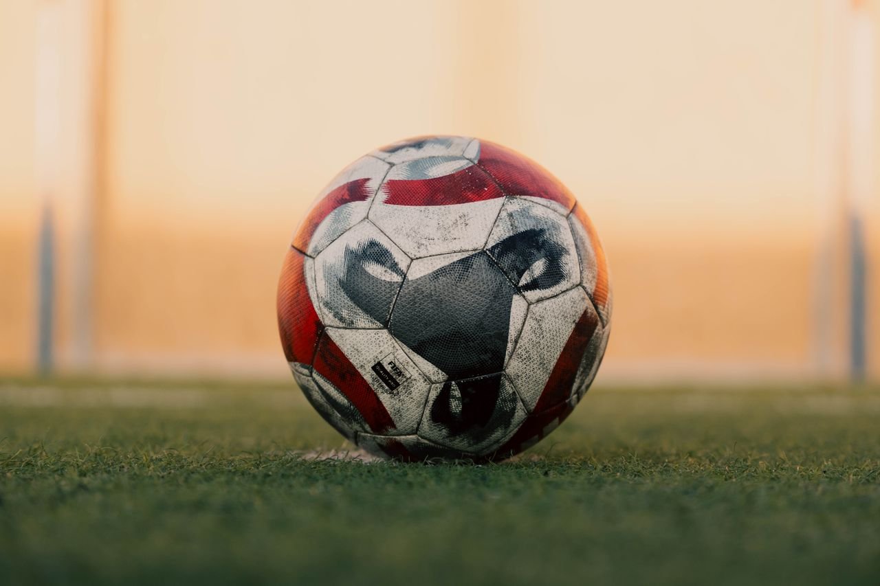 Close-up of a soccer ball on a grassy field in Libya during sunset.