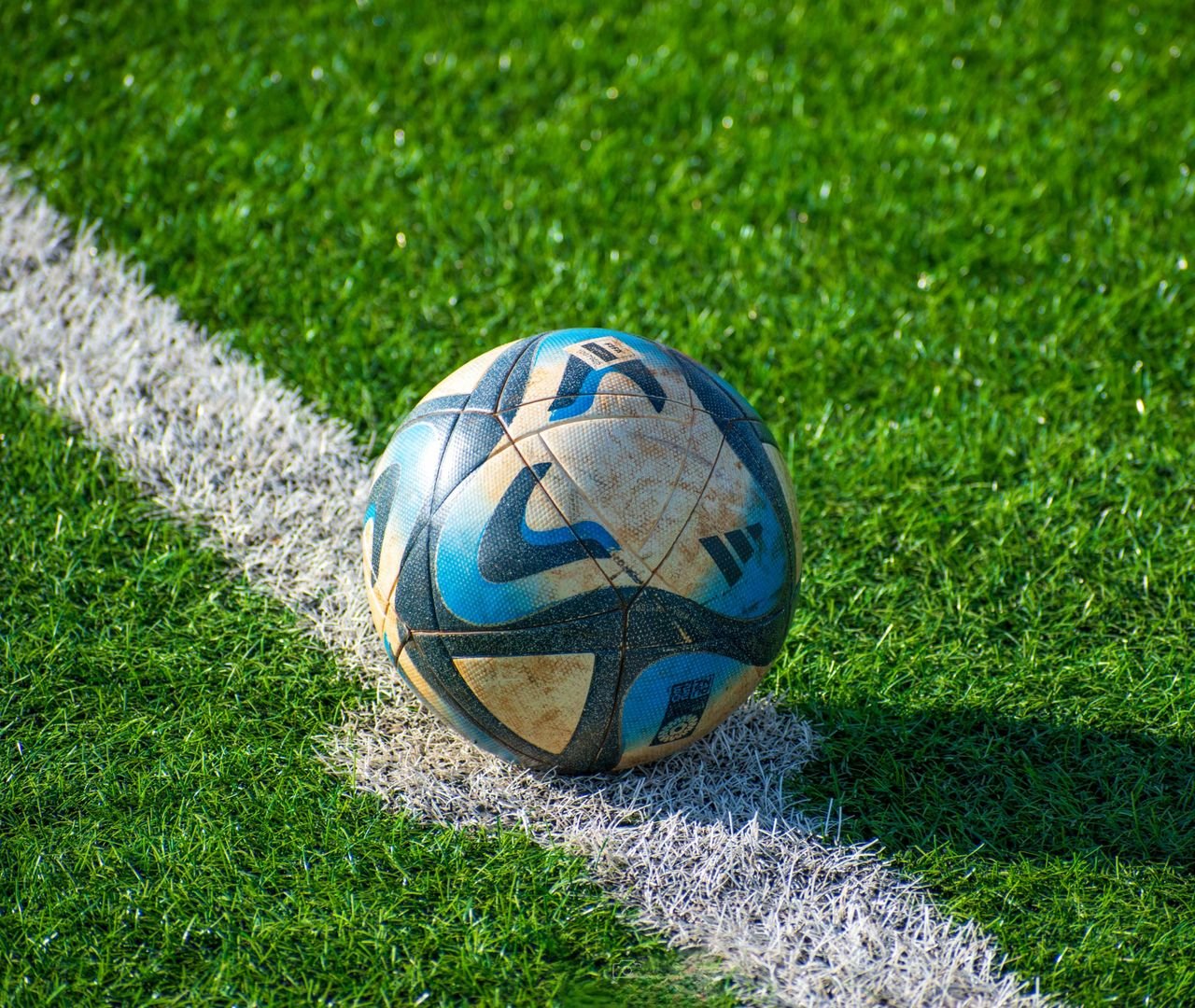 A soccer ball rests on a vibrant green football field, ready for action.