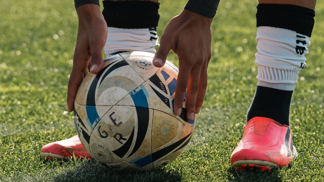 The Art of Drawing Readers In: Your attractive post title goes here Close-up of a soccer player setting the ball on a grassy field, ready to take a shot.